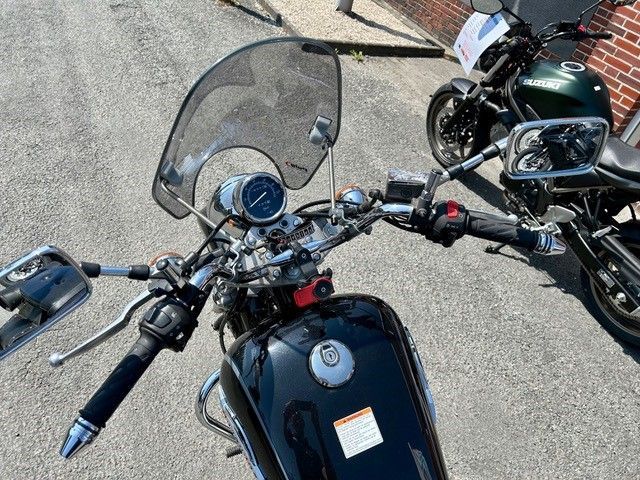 Ein schwarzes Motorrad mit Windschutzscheibe ist neben einem anderen Motorrad geparkt.