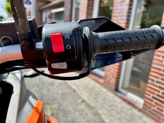 Eine Nahaufnahme eines Motorradlenkers mit einem roten Knopf darauf.