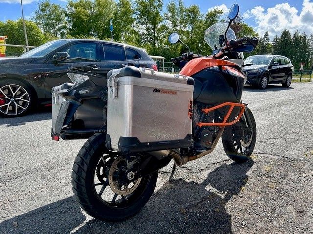 Auf einem Parkplatz steht ein Motorrad neben einem Auto.