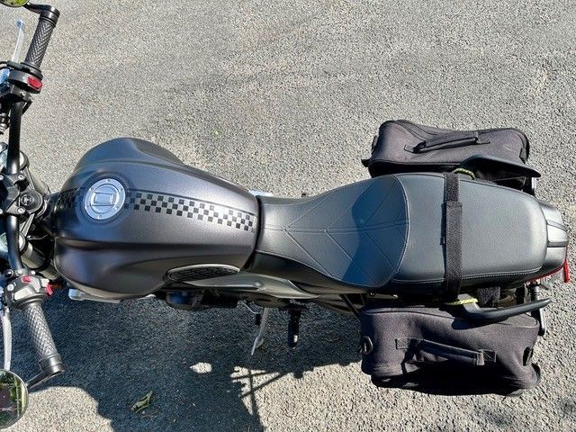 Draufsicht auf ein schwarzes Motorrad mit karierten Akzenten auf dem Benzintank und daran befestigten schwarzen Satteltaschen.