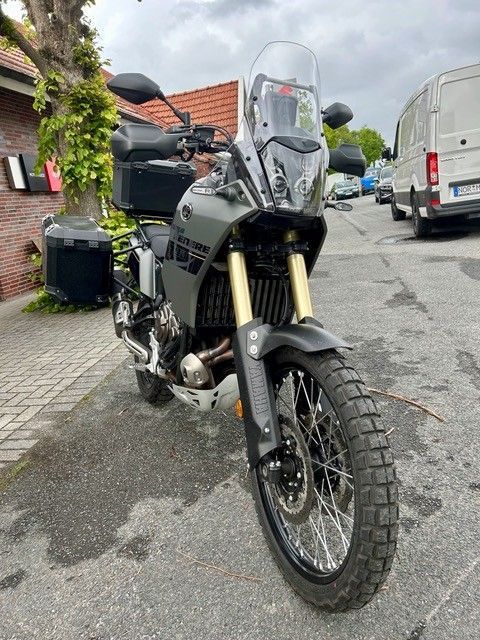 Adventure-Motorrad parkt in einer Wohnstraße, Frontansicht mit hoher Windschutzscheibe und Stollenreifen.