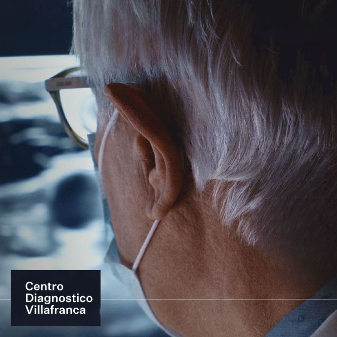 Medico che osserva una scansione medica, con occhiali e mascherina. Logo del 