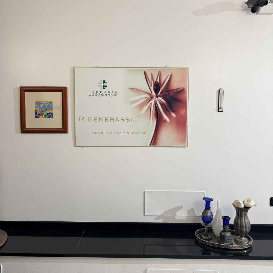 Parete bianca con quadri incorniciati e un cartello. Piano di lavoro nero con elementi decorativi.