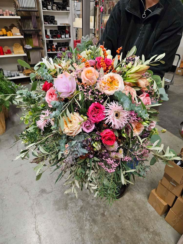 Ein Mann hält in einer Lagerhalle einen großen Blumenstrauß.