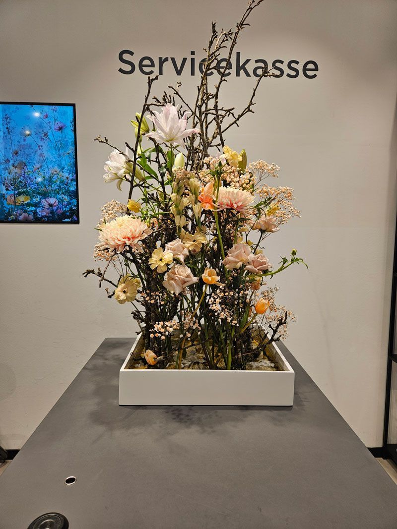 Auf einem Tisch steht eine mit Blumen gefüllte Vase.