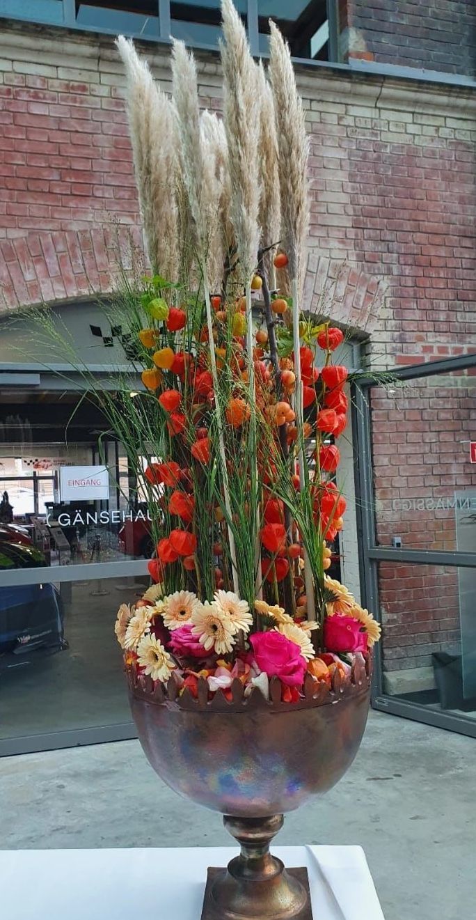 Zwei mit Blumen gefüllte Vasen stehen auf einem Tisch vor einem Fenster.