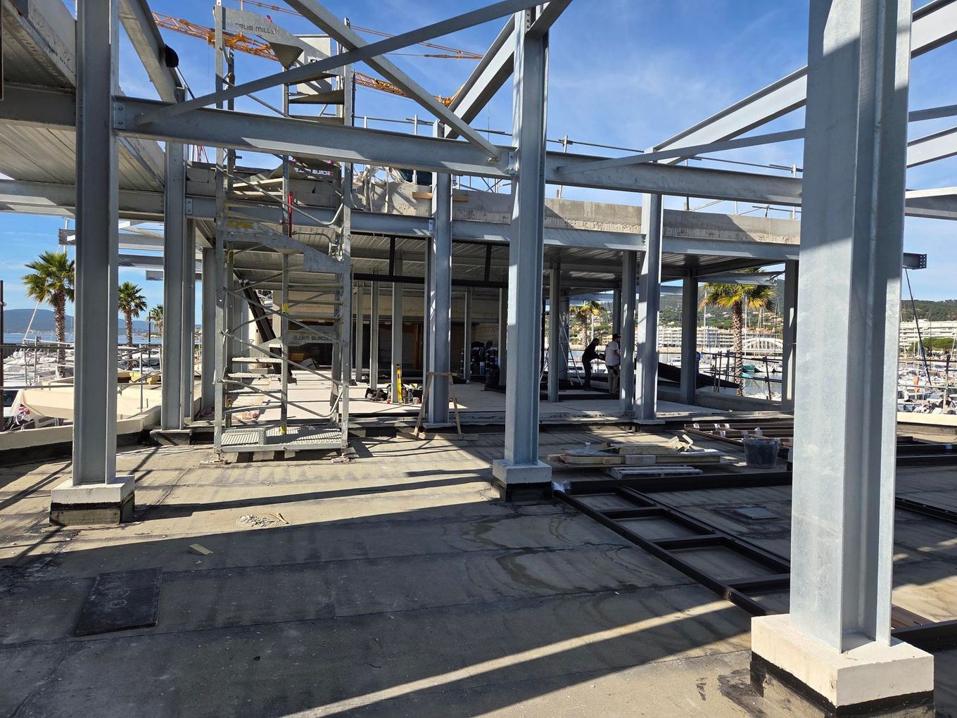 Structure en béton et en acier partiellement construite près d'une plage de sable sous un ciel bleu