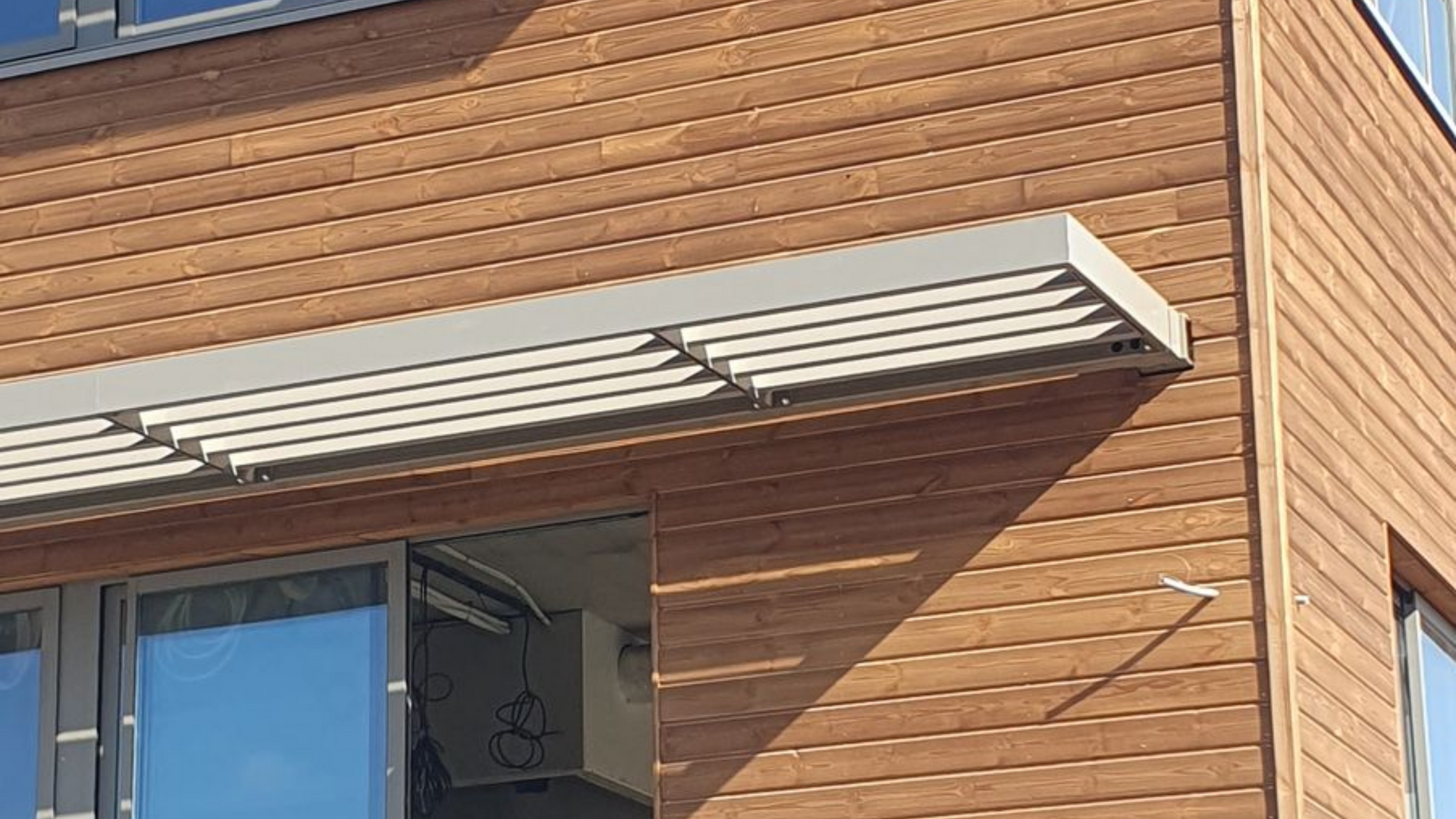 Façade d'immeuble avec un auvent blanc et une fenêtre à cadre bleu sur un revêtement brun