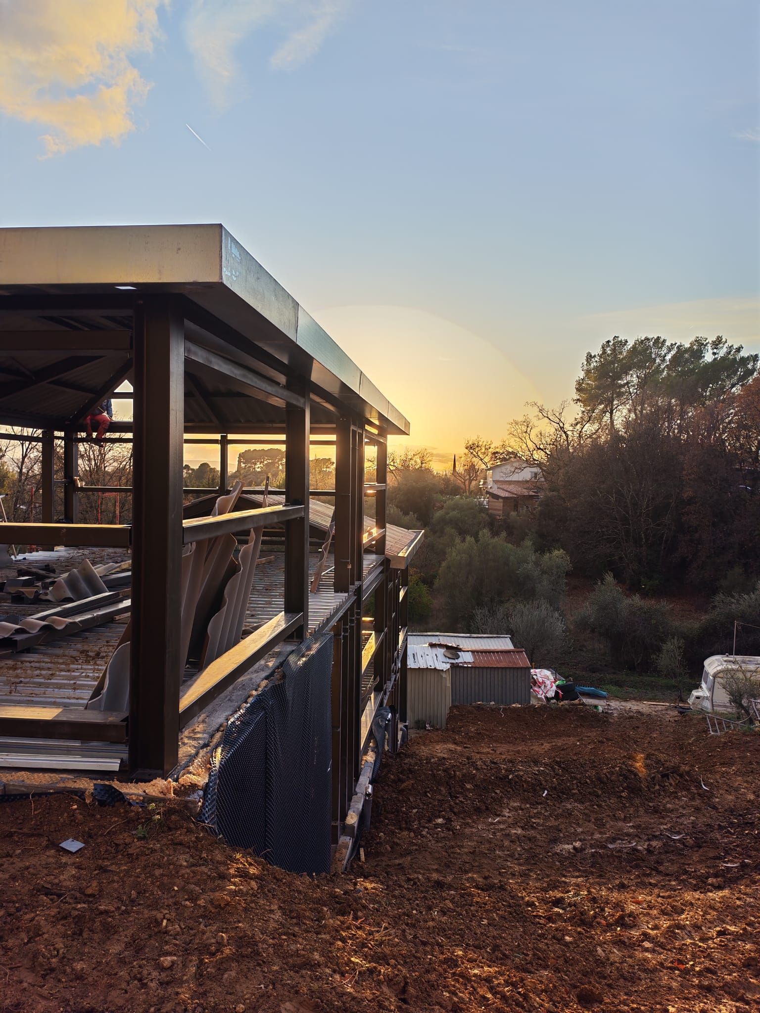 Coucher de soleil sur une terrasse vitrée avec des arbres et un jardin recouvert de feuilles