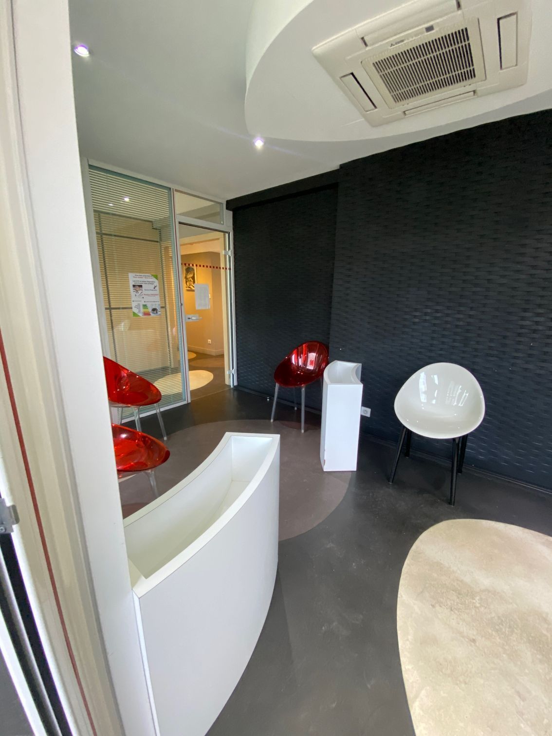 Salle d'attente avec des fauteuils blancs et rouges.