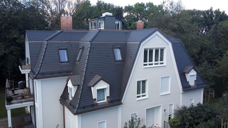 Ein hohes, weißes Wohnhaus mit schwarzen Dachziegeln