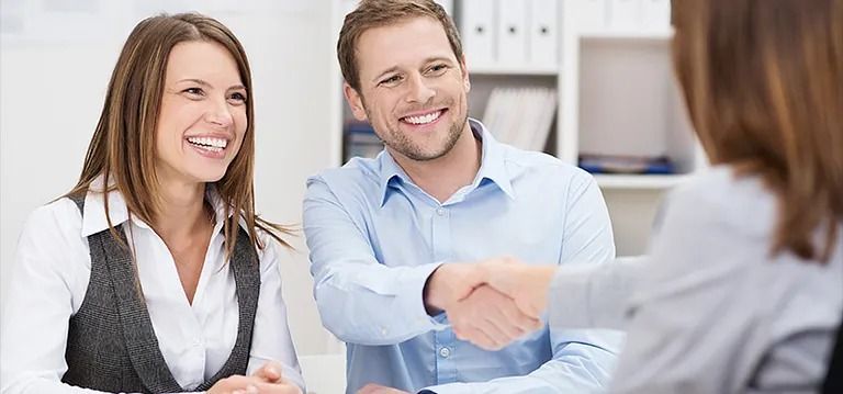 Un hombre y una mujer se dan la mano mientras están sentados en una mesa.