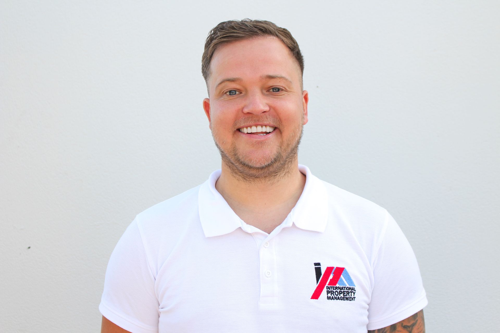 Un hombre que lleva un polo blanco sonríe a la cámara.