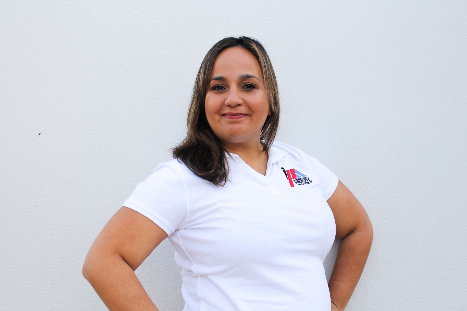 Una mujer con una camisa blanca está parada frente a una pared blanca.