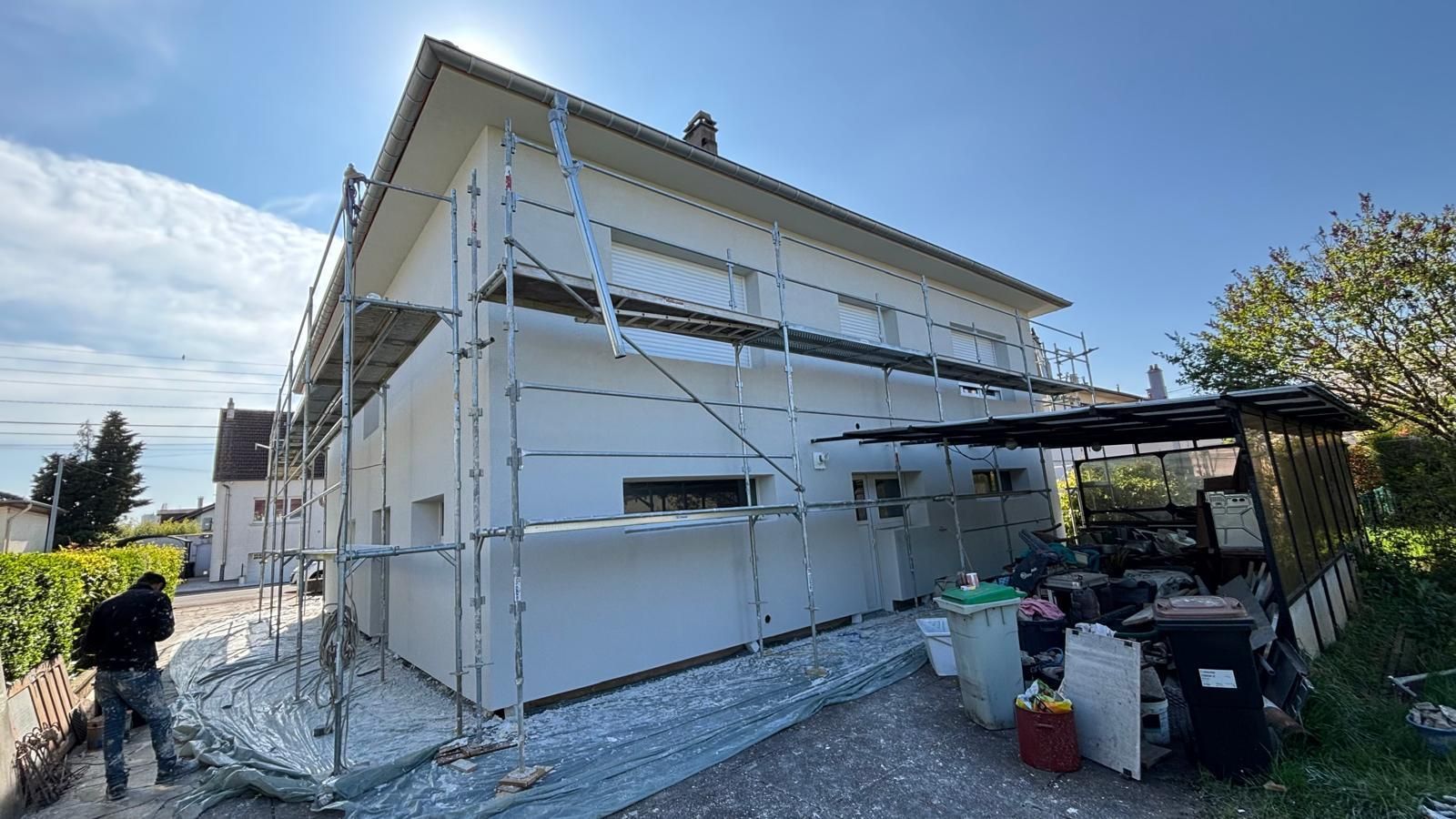 Maison en rénovation avec échafaudage. Murs extérieurs blancs.