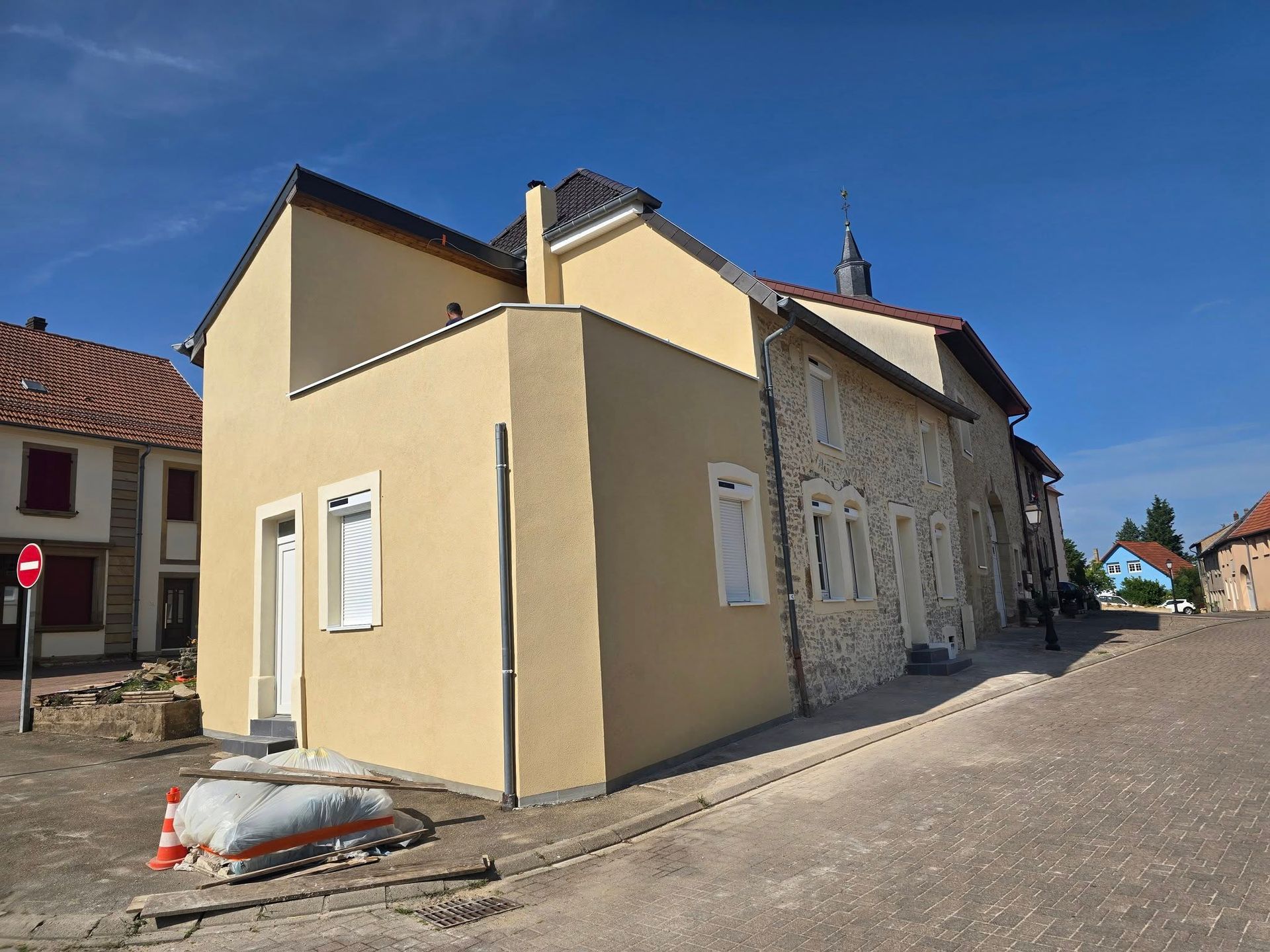 Bâtiment jaune avec façade en pierre, rue, ciel bleu, matériaux de construction.