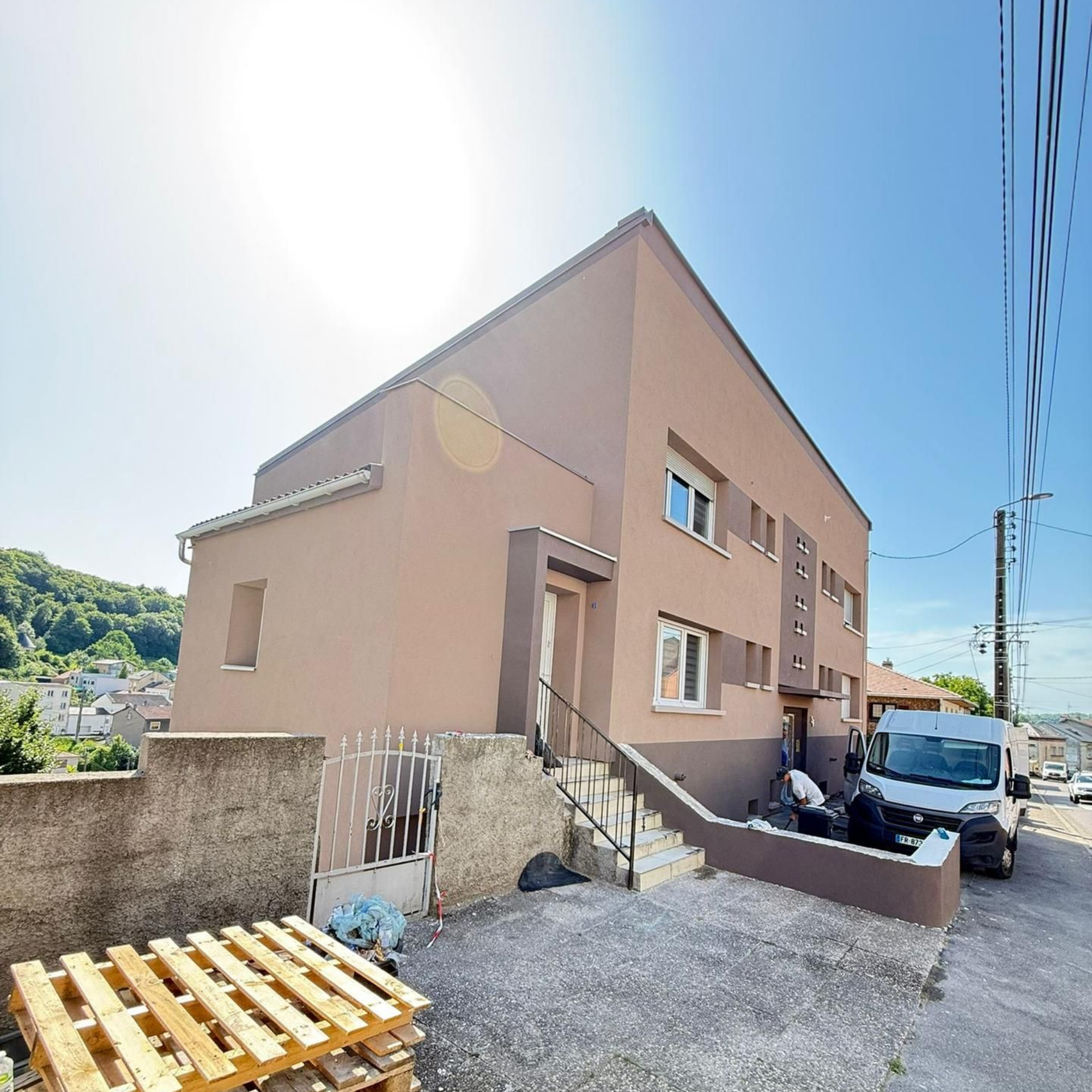 Bâtiment de deux étages, petite entrée fermée, camionnette garée devant.