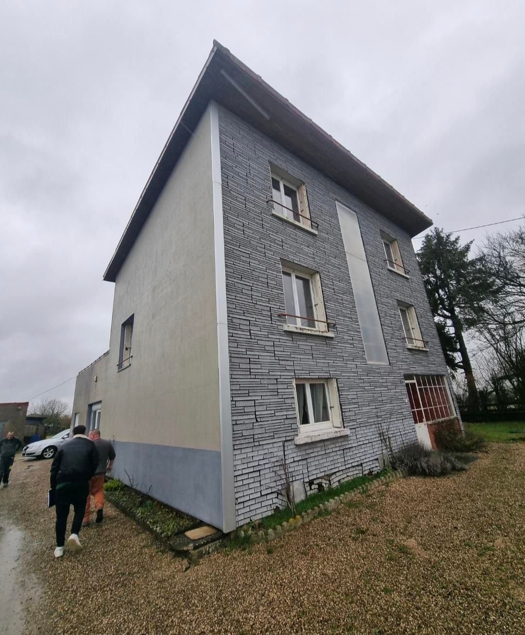 Maison à deux étages avec revêtement en pierre grise et partie gris clair.