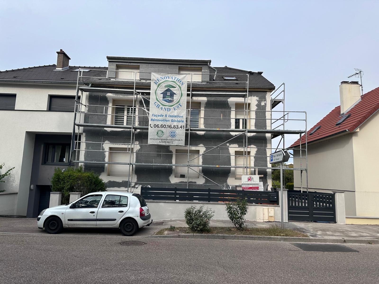 Maison en rénovation avec échafaudage; voiture blanche garée devant.