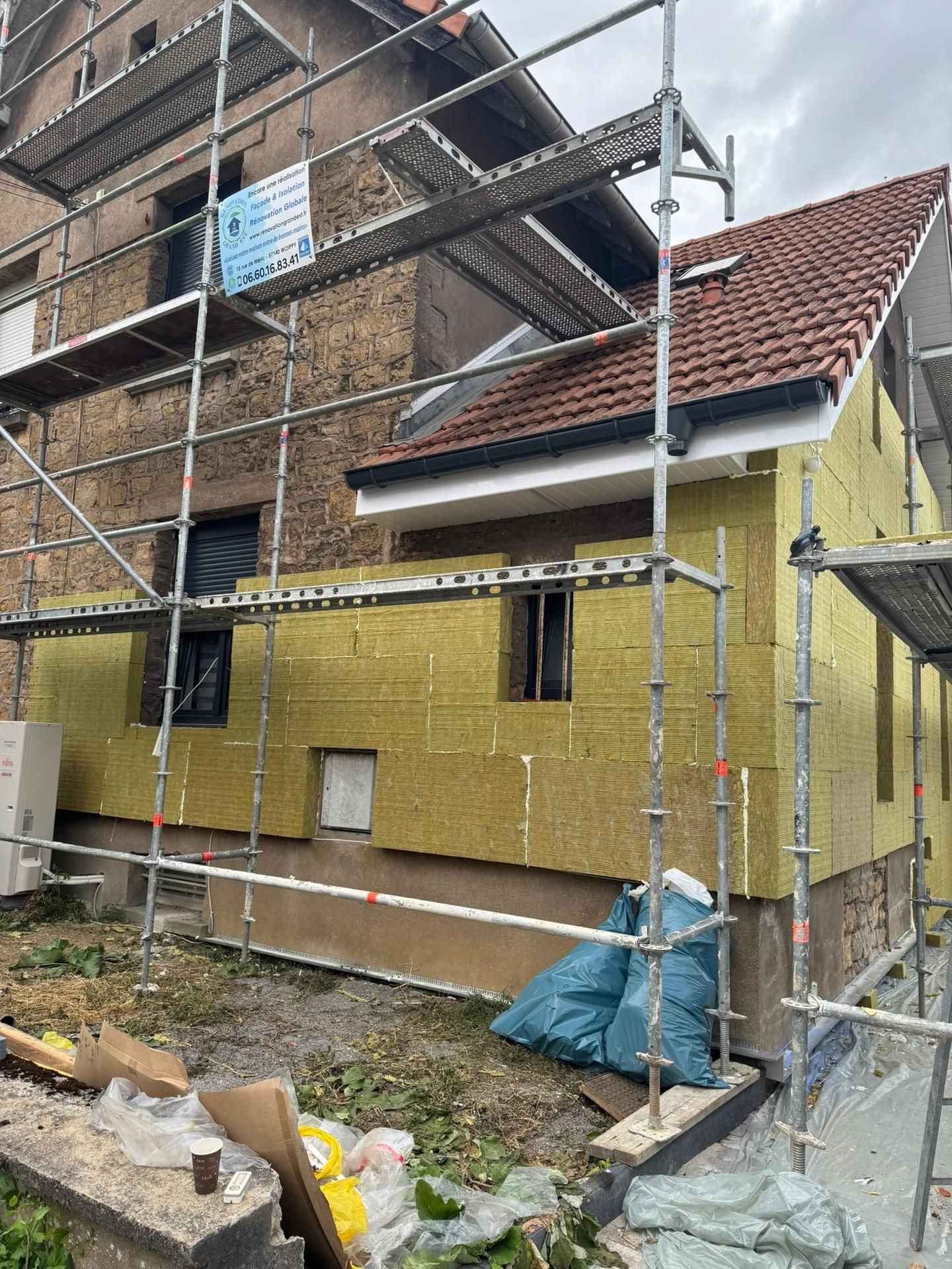 Extérieur maison en cours de rénovation avec échafaudage et isolation.