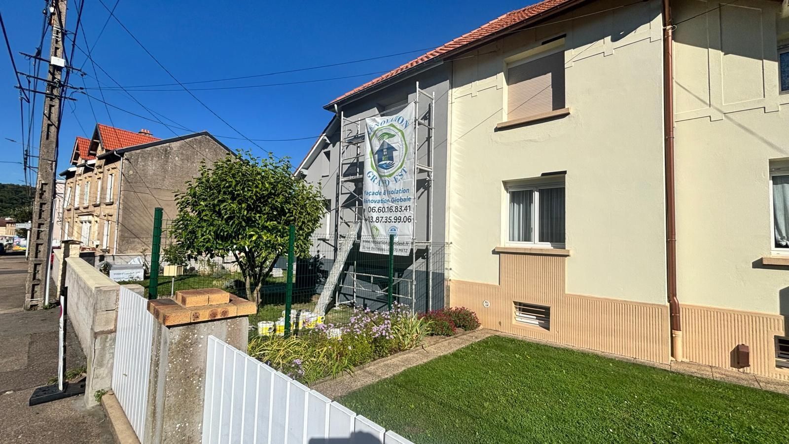 Un bâtiment de deux étages avec une pelouse verte et un petit jardin.