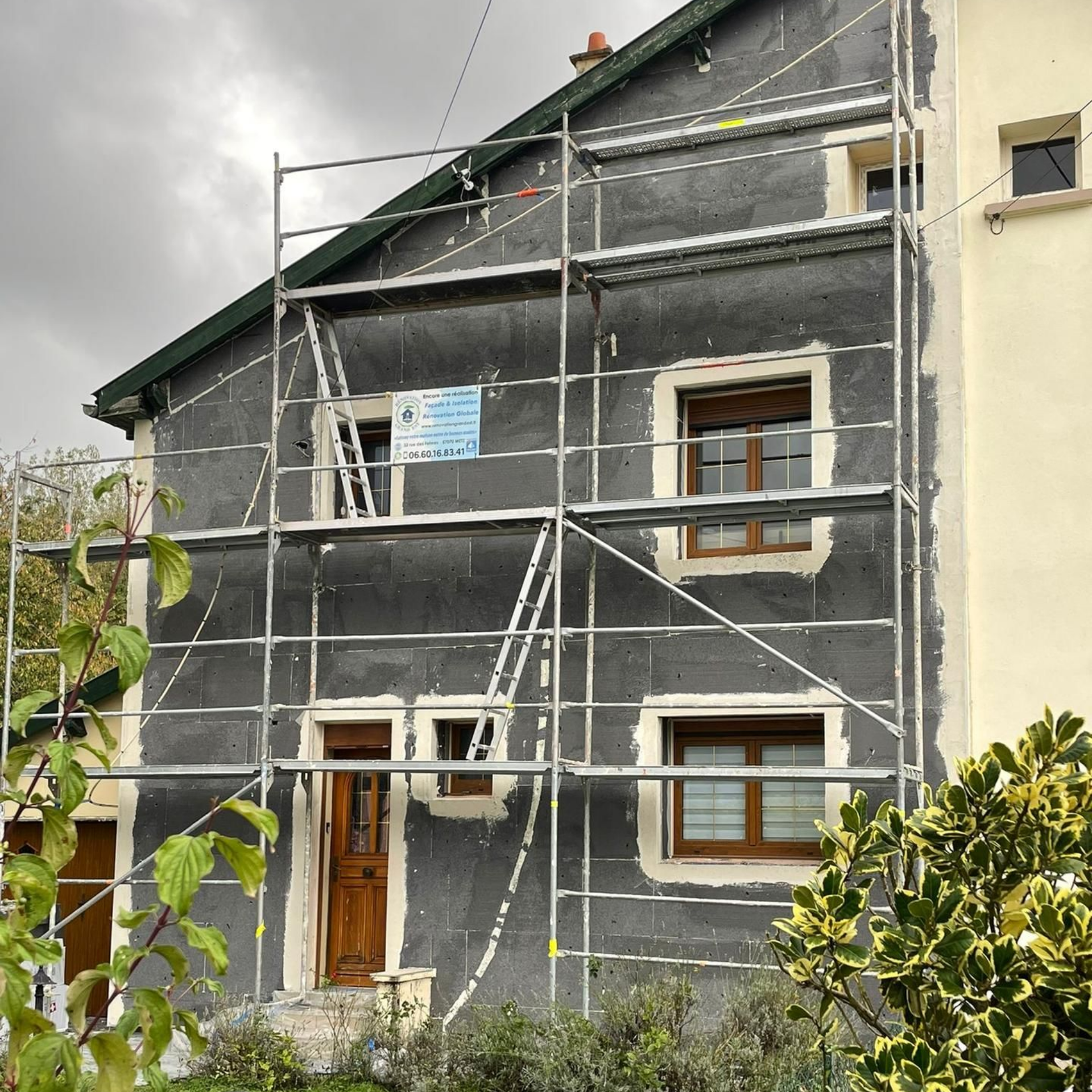 Extérieur de maison en construction avec échafaudage, isolation visible.
