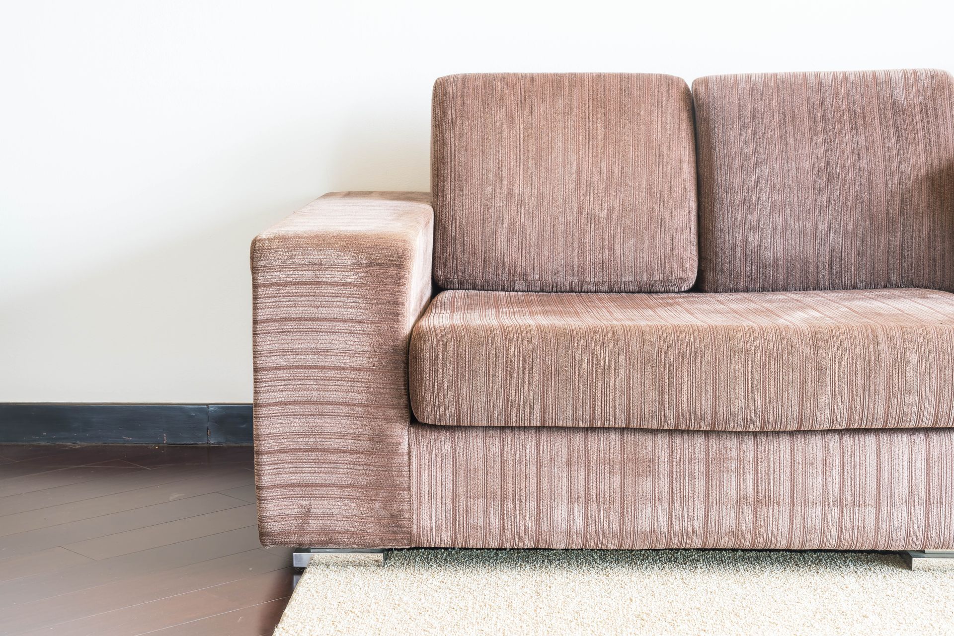 En un taller, una persona utiliza una grapadora neumática para fijar tela al armazón de madera de un mueble.
