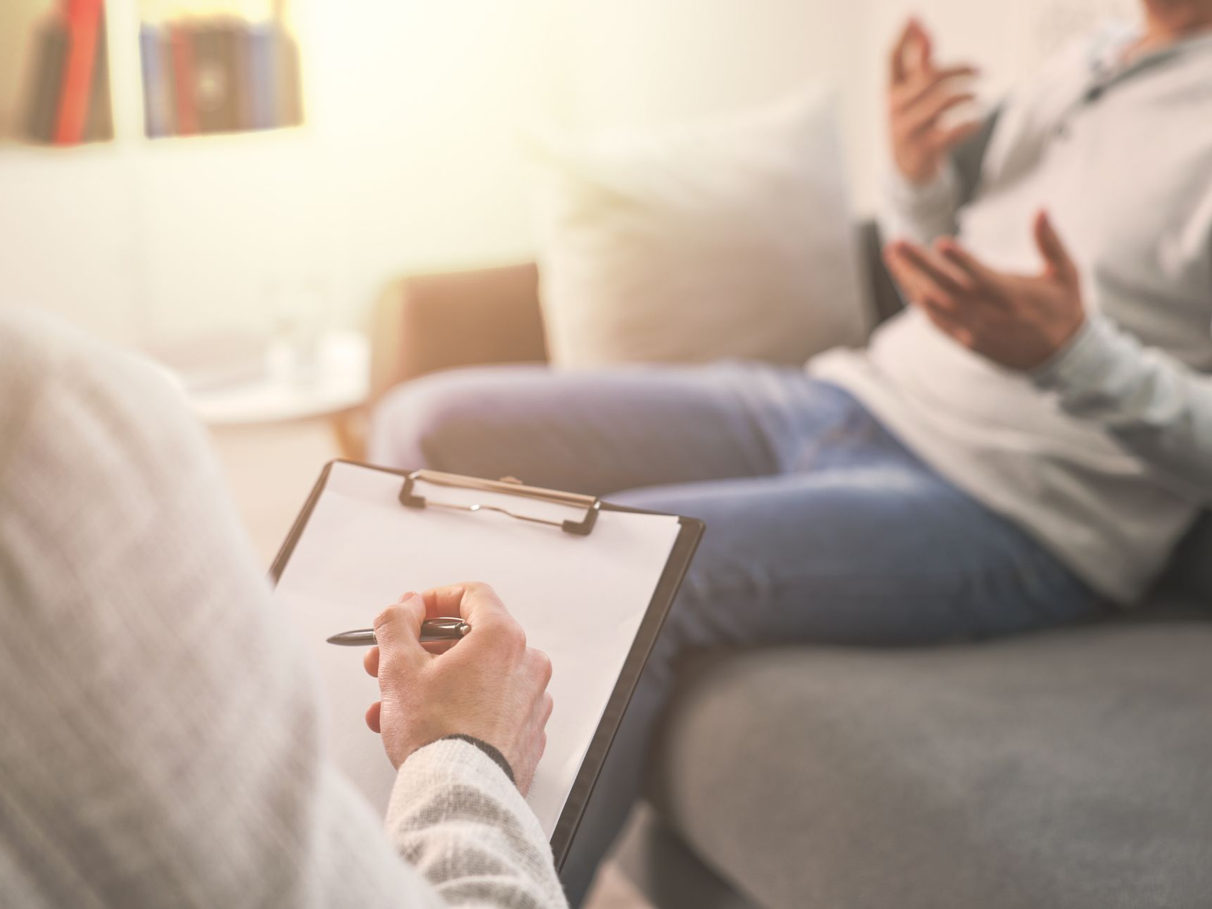 Une personne assise sur un canapé fait des gestes tandis qu'une autre prend des notes.