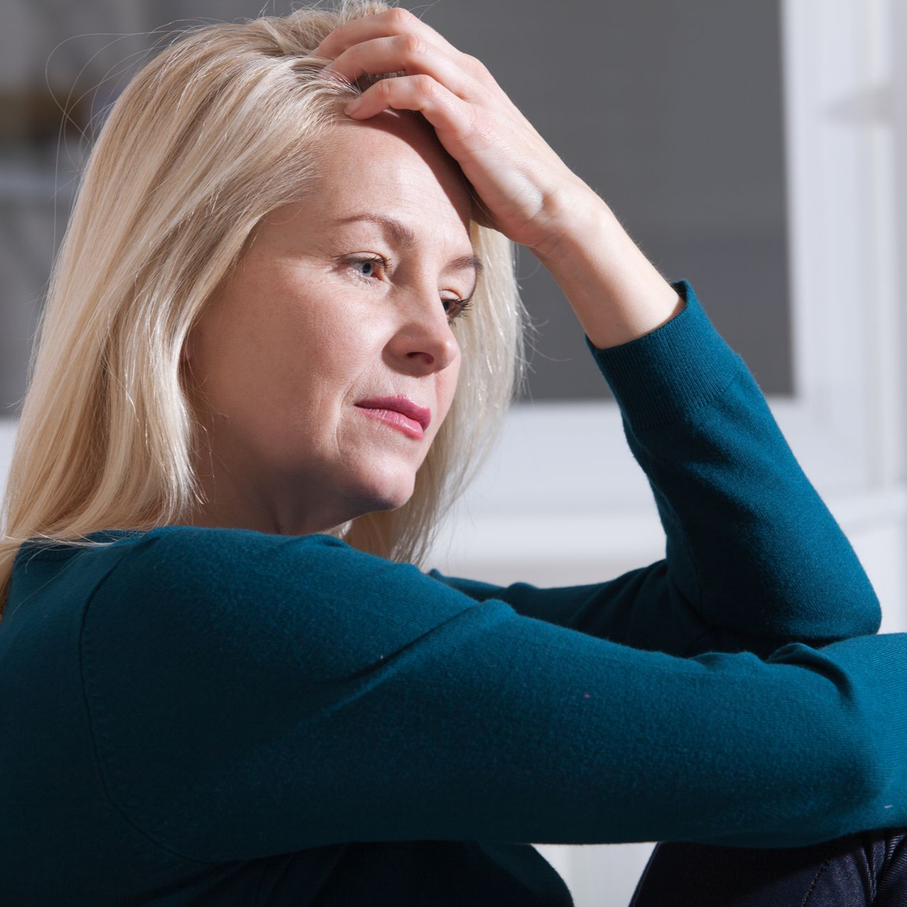 Femme aux cheveux blonds, la tête appuyée sur la main.