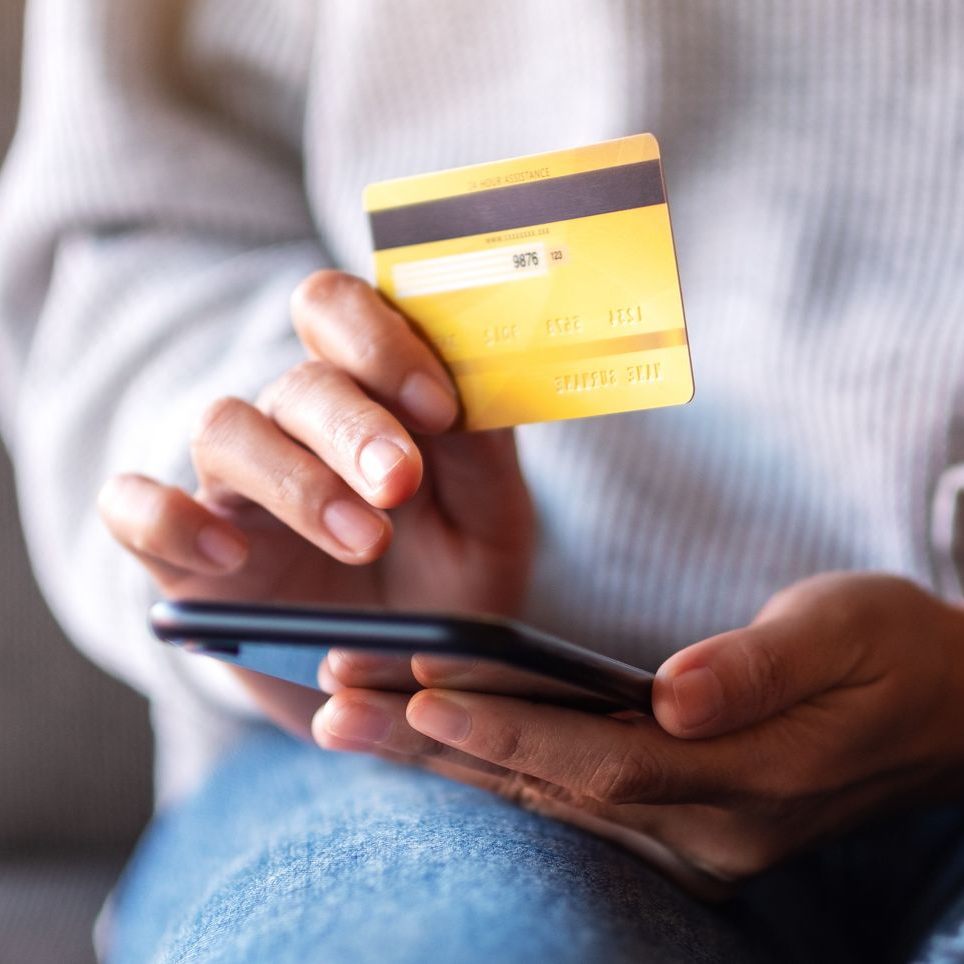 Personne tenant une carte de crédit et un smartphone noir.
