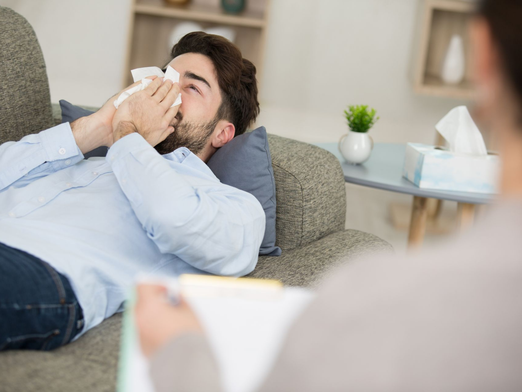 Un homme allongé sur un canapé se mouche se confiant à un thérapeute.