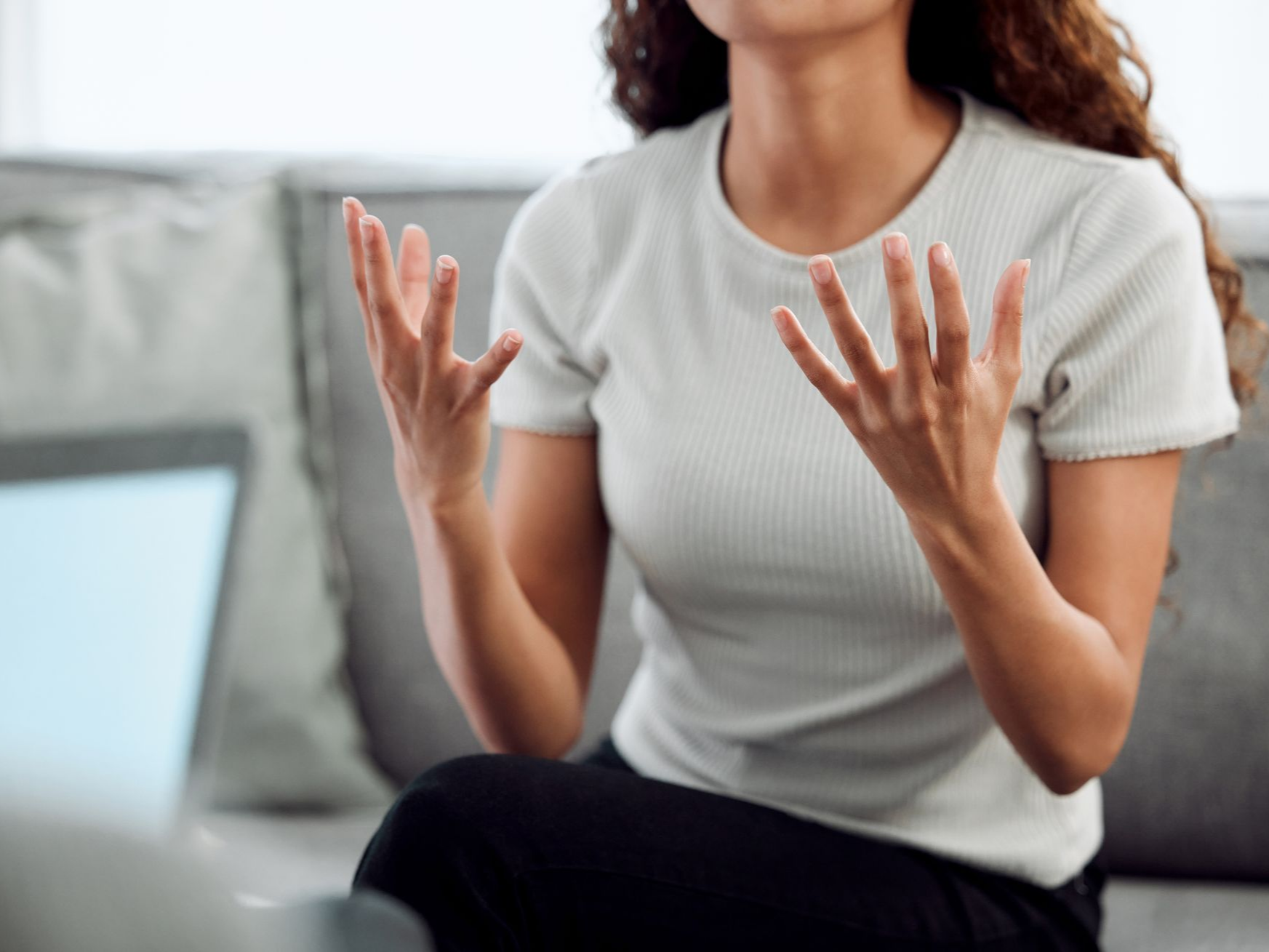 Femme assise, gesticulant et parlant à une personne.