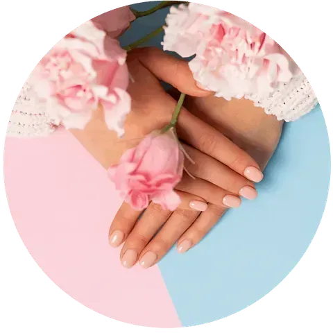 Manos con esmalte de uñas rosa sosteniendo flores rosas sobre un fondo rosa y azul.