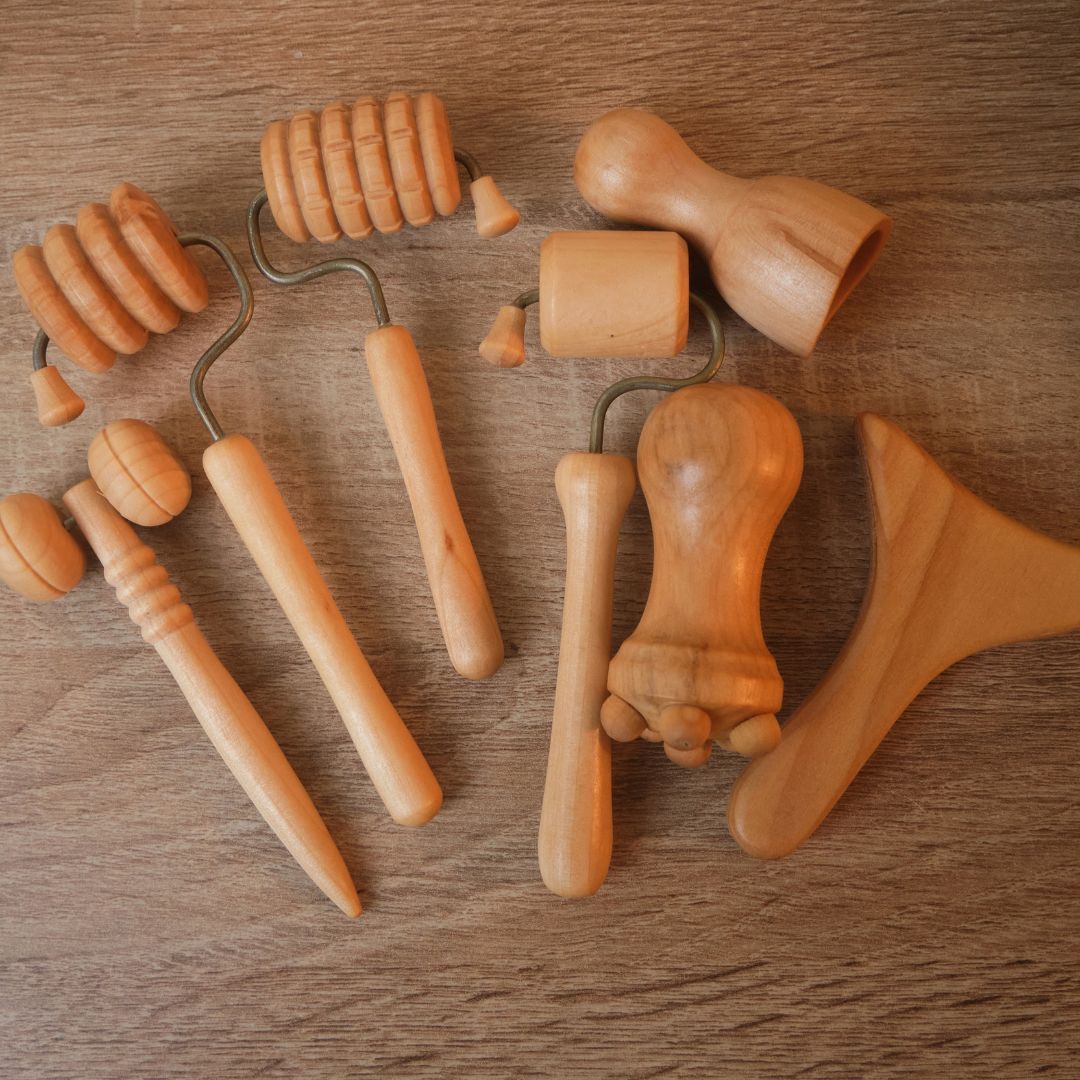 Herramientas de masaje de madera sobre una superficie de madera. Diversas formas, como rodillos, cabeza de hongo y espátula.