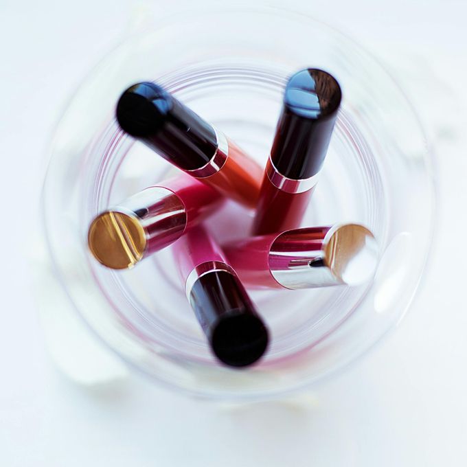 Lippenstifte in verschiedenen Farbtönen in einem durchsichtigen Glasbehälter, von oben betrachtet.