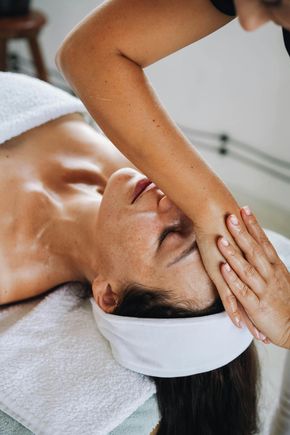 Frau erhält Gesichtsbehandlung, lächelnd, hellhäutig, blondes Haar, Salon-Ambiente, behandschuhte Hände, medizinisches Gerät.