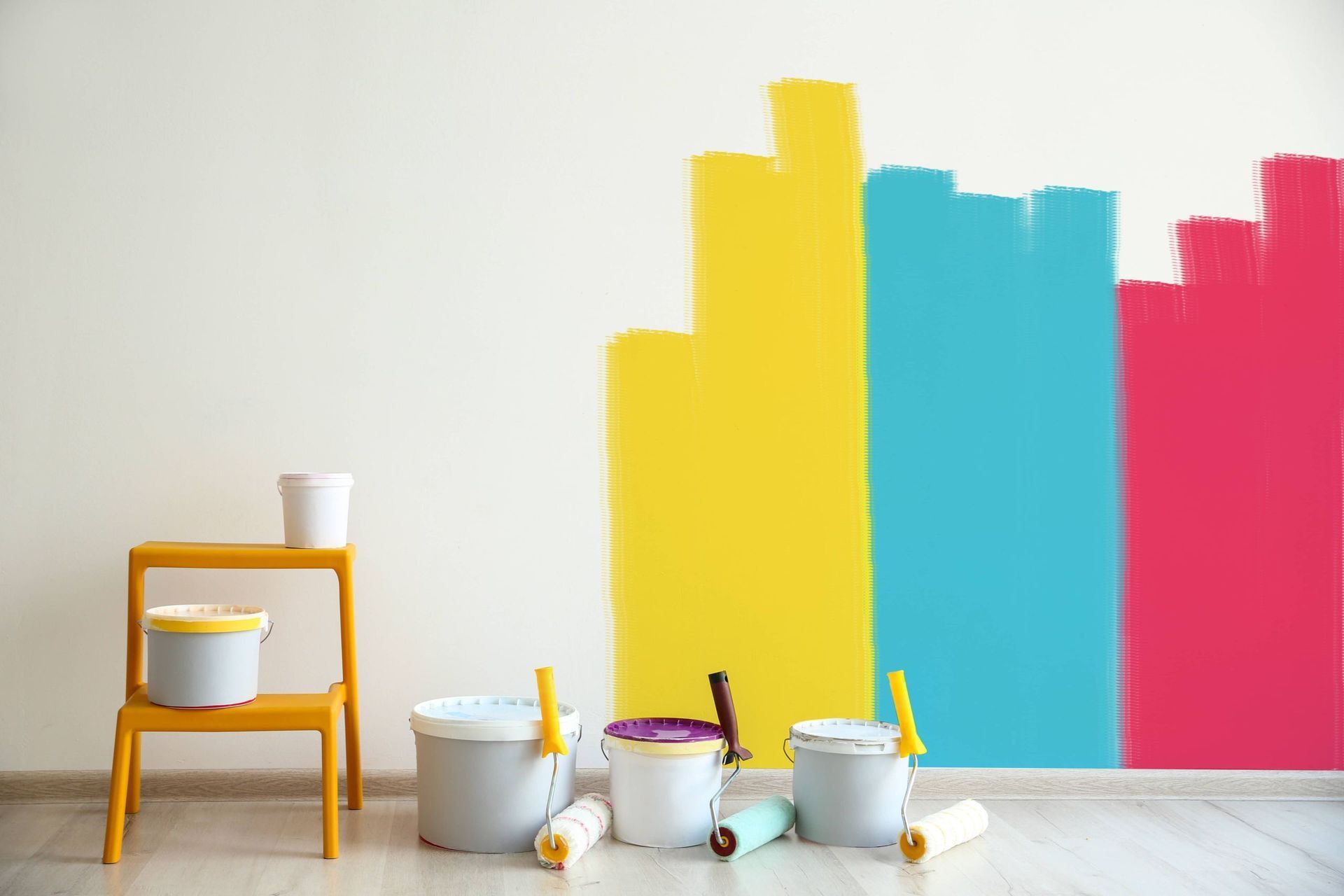 Un mur est peint de différentes couleurs avec des pots de peinture et des rouleaux.