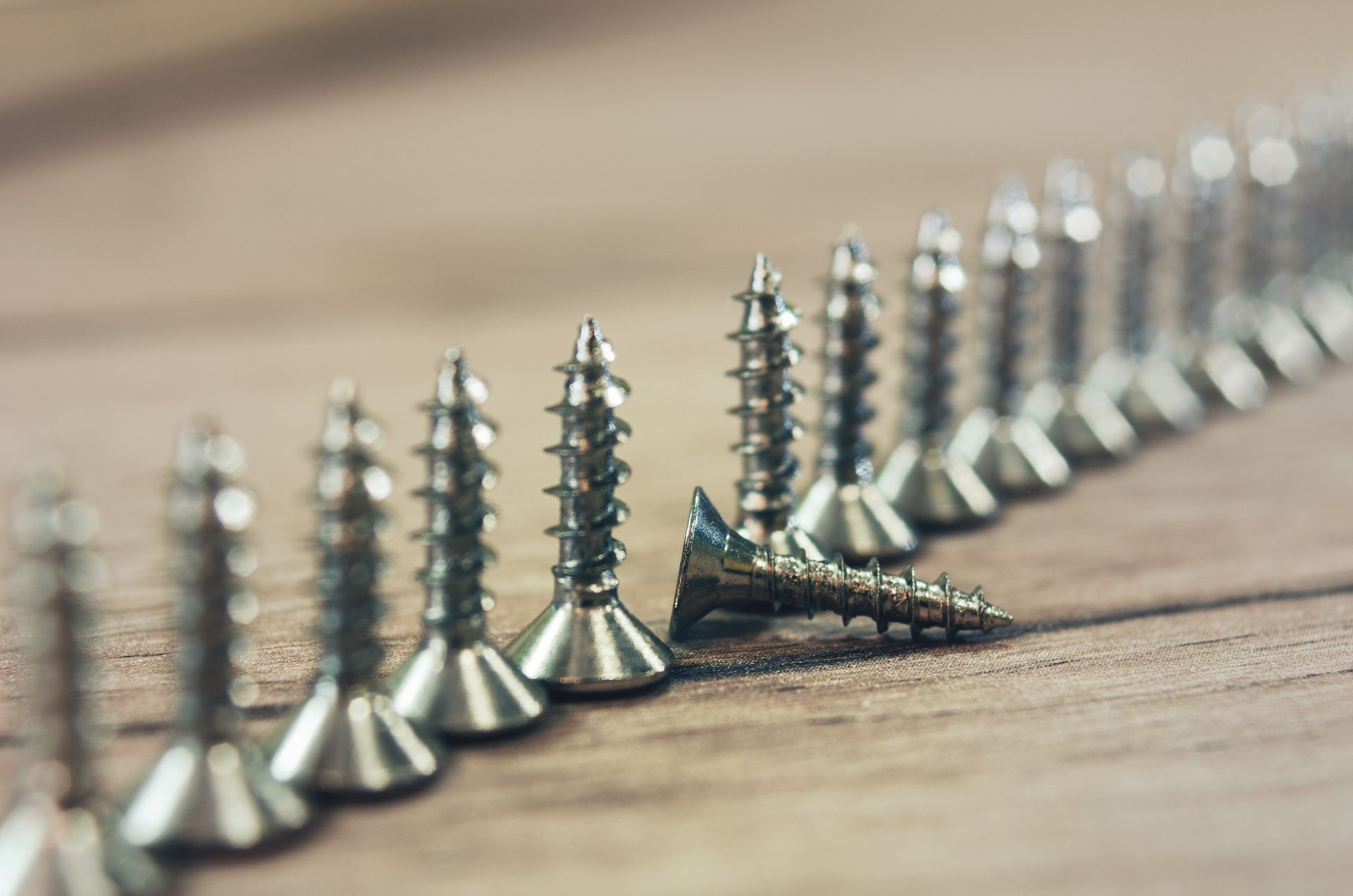 Una fila de tornillos están alineados en una fila sobre una mesa de madera.