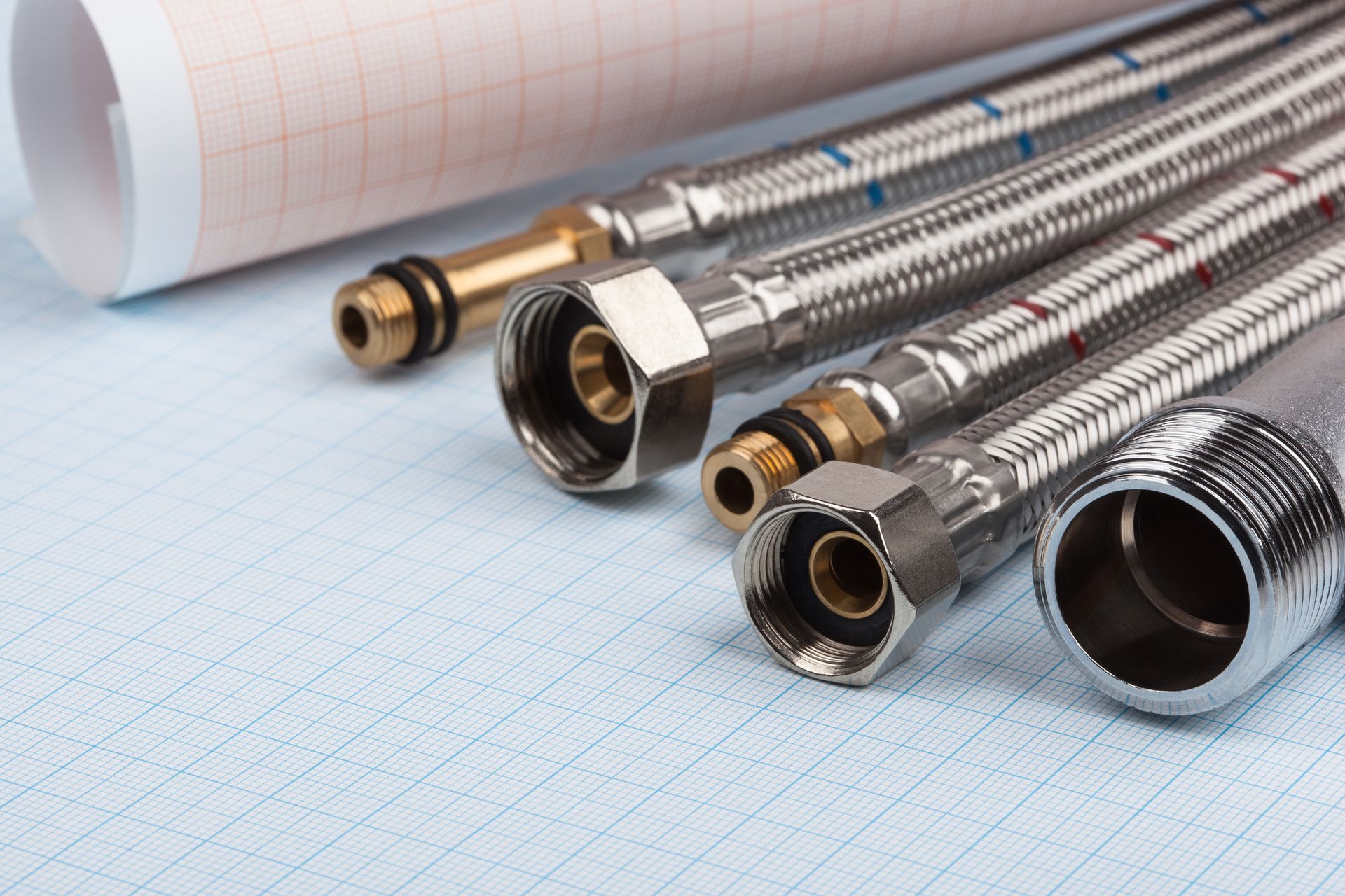 Un montón de tubos de metal están colocados encima de un trozo de papel cuadriculado.