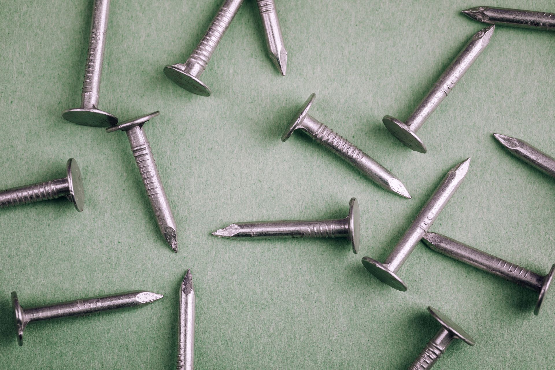 Un montón de clavos yacen sobre una superficie verde.