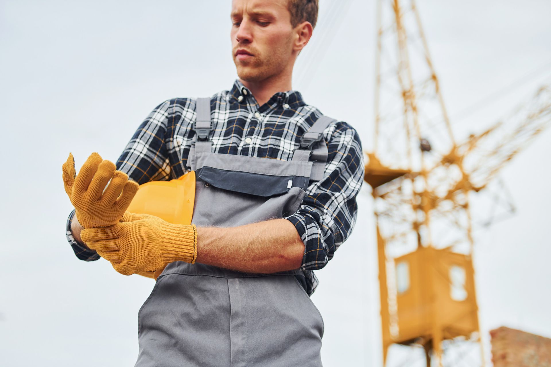 Un trabajador de la construcción se pone los guantes en una obra en construcción.