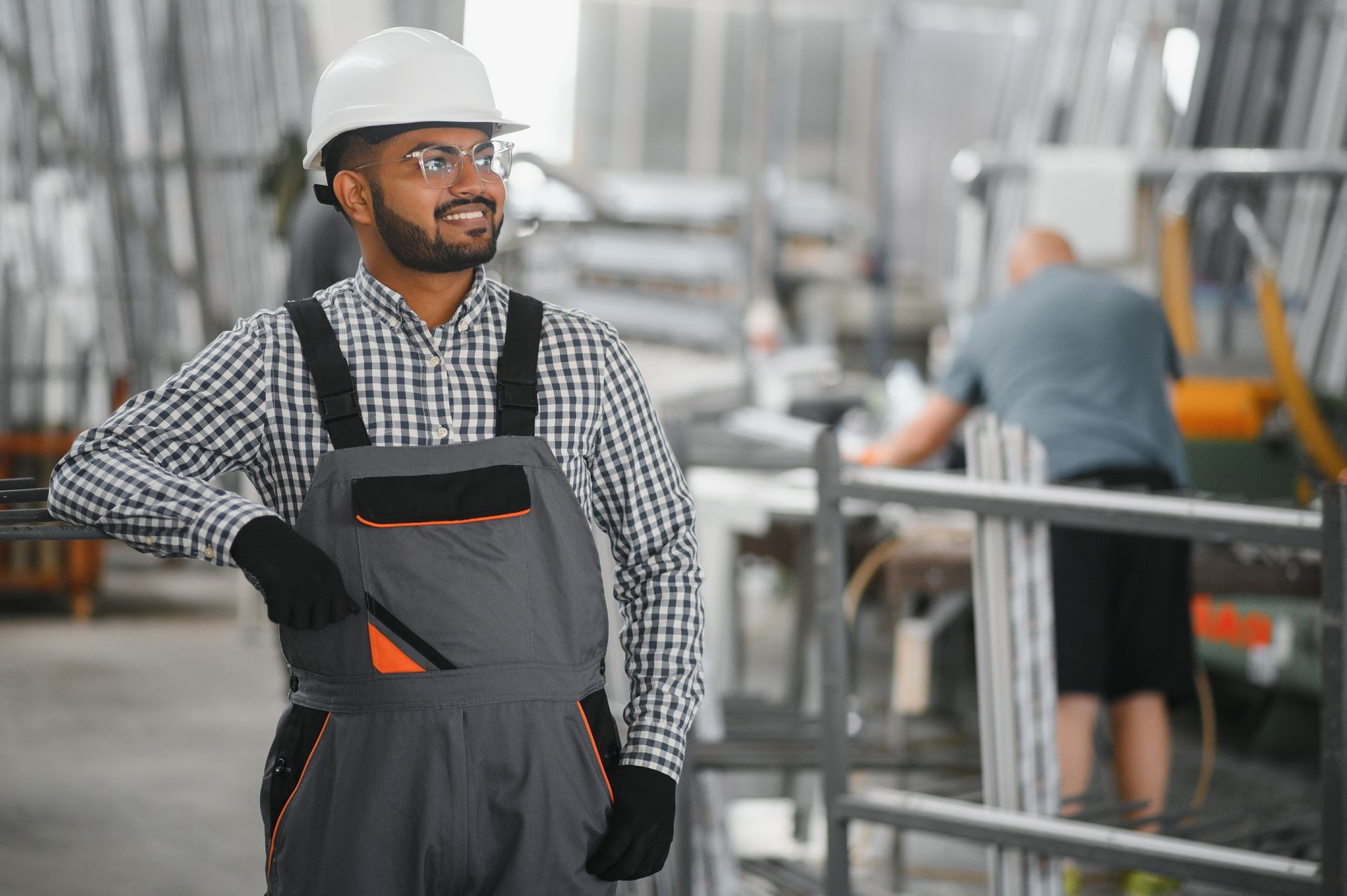 Un hombre con mono y casco está de pie en una fábrica.