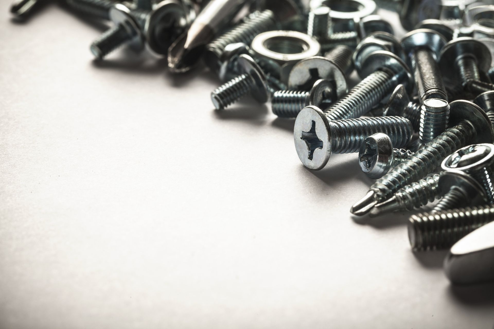 Una pila de tornillos y tuercas sobre una superficie blanca.