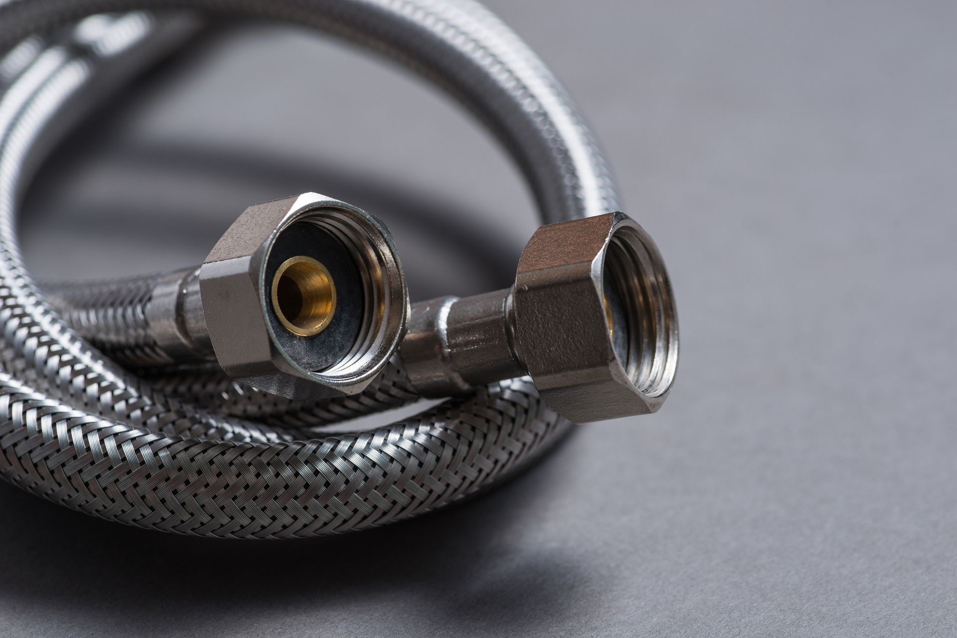 Un primer plano de una manguera de metal sobre una superficie gris.