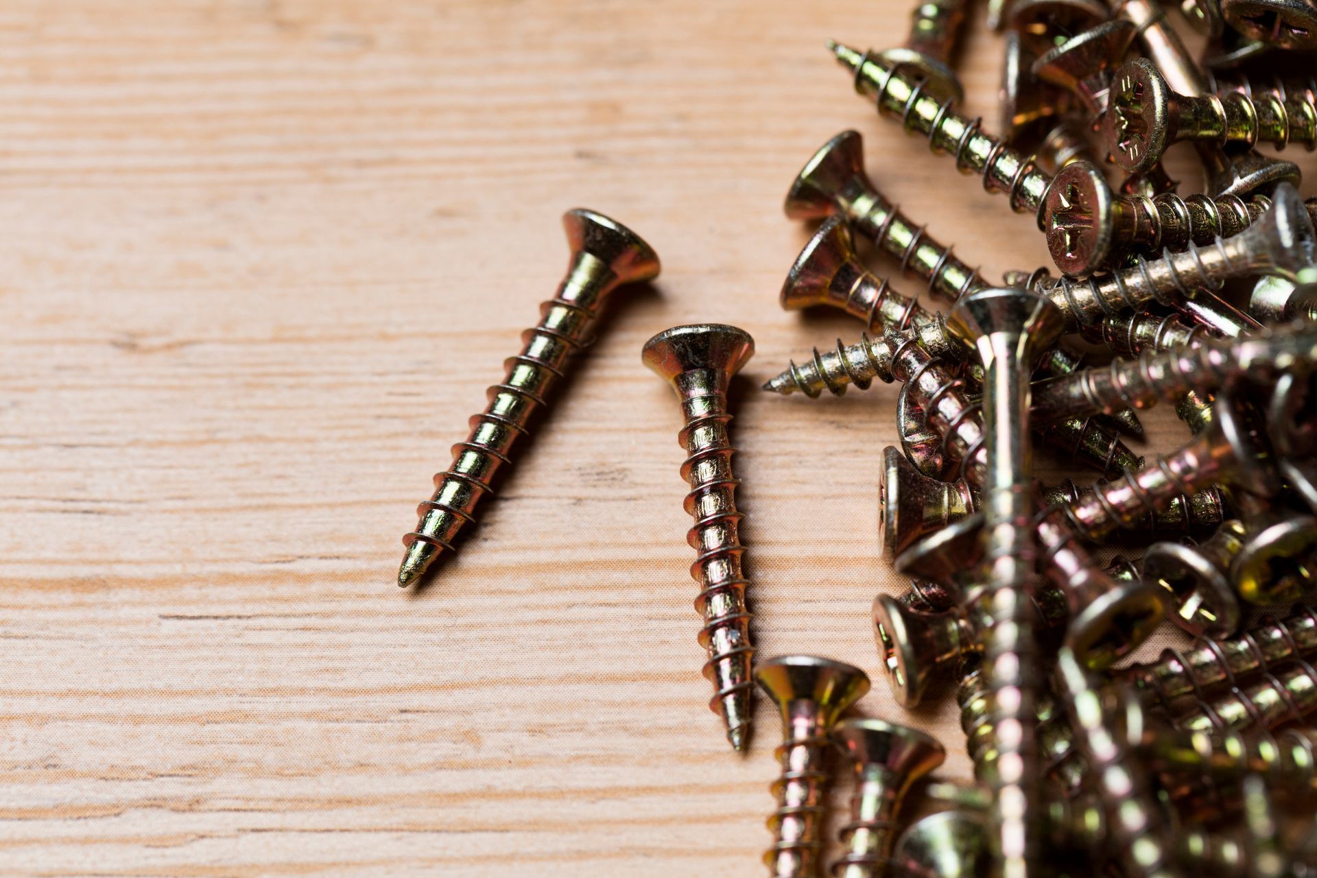 Una pila de tornillos encima de una mesa de madera.