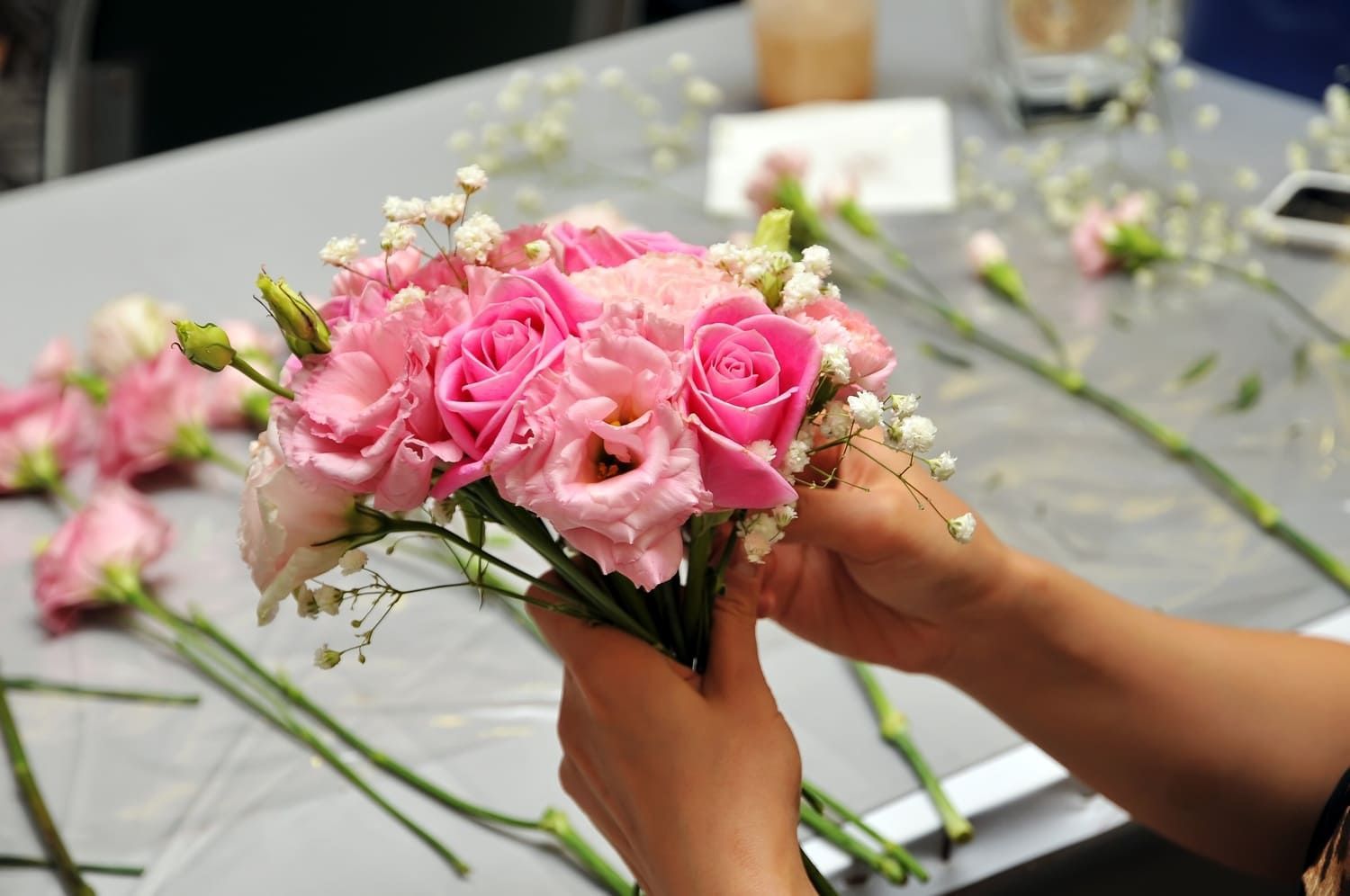 Una persona sostiene un ramo de rosas rosadas y flores de bebé.