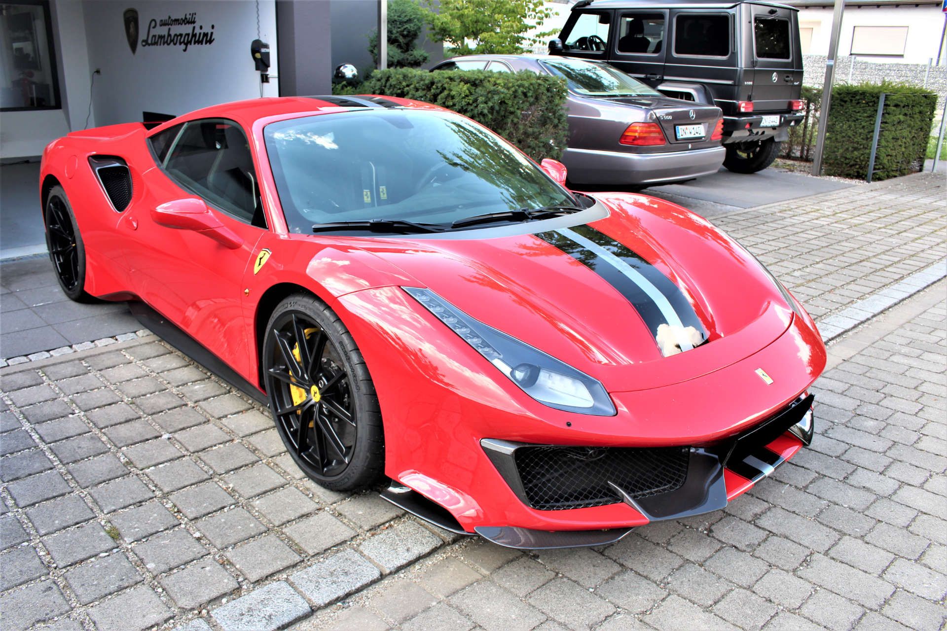 Roter Ferrari 488 GTB mit schwarzem Streifen in einer Einfahrt