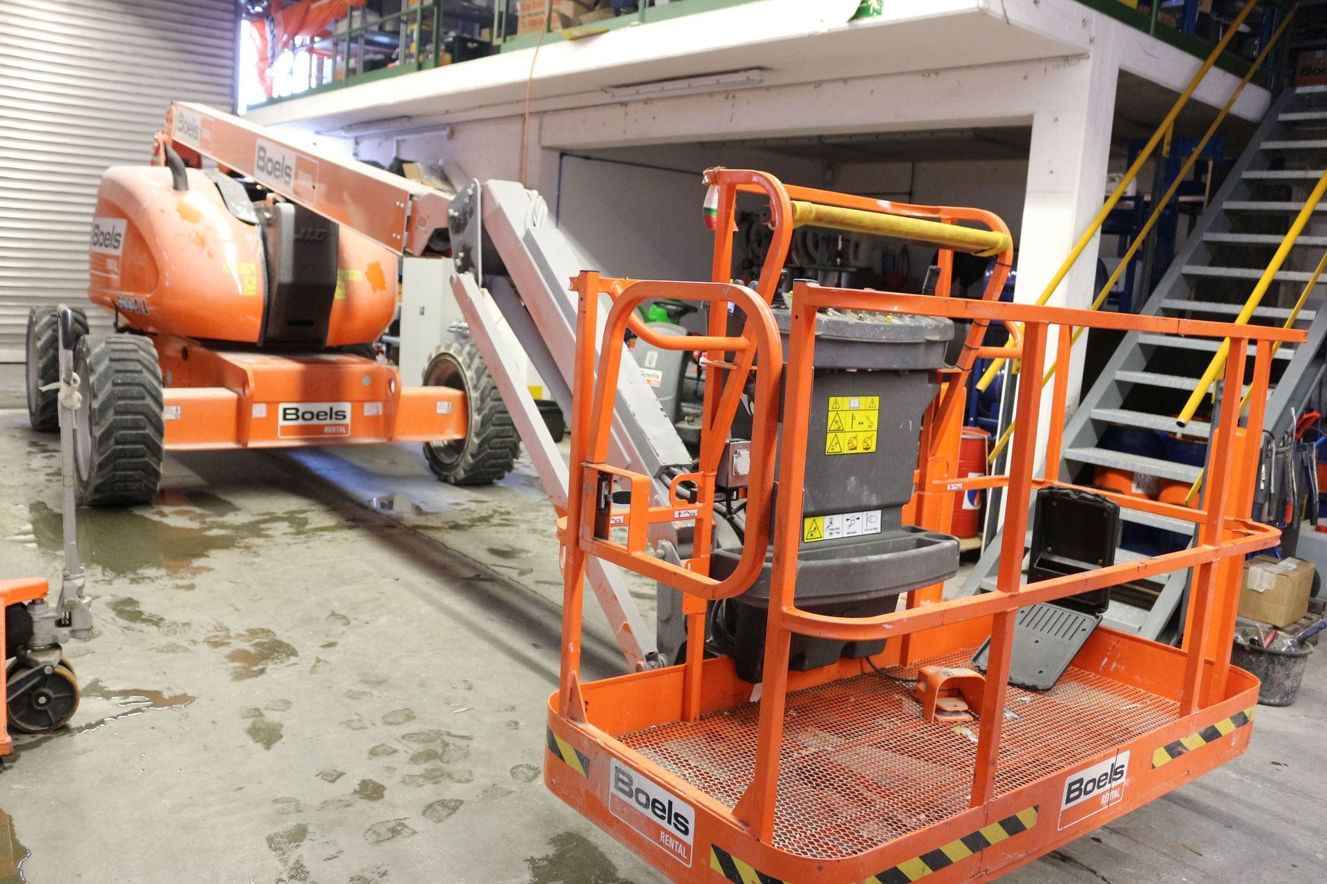 Oranger Arbeitsbühnenkorb mit Geländer und Steuerung, verbunden mit einem Teleskoparm.