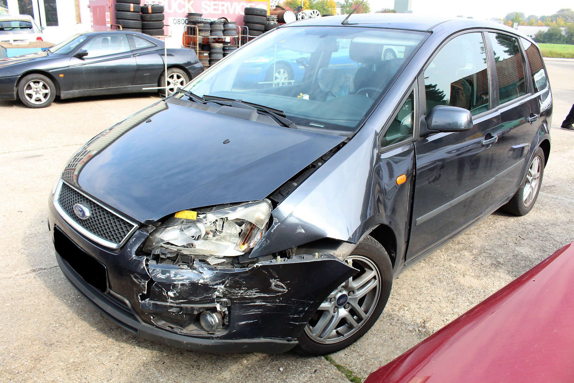 Schwarzer Ford C-Max mit beschädigtem vorderem linken Kotflügel und Scheinwerfer.