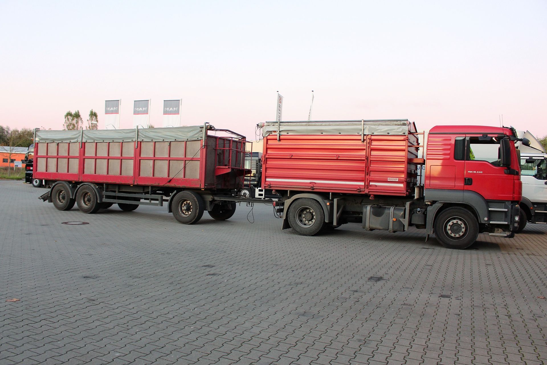 Roter LKW mit Anhänger hinten dran.